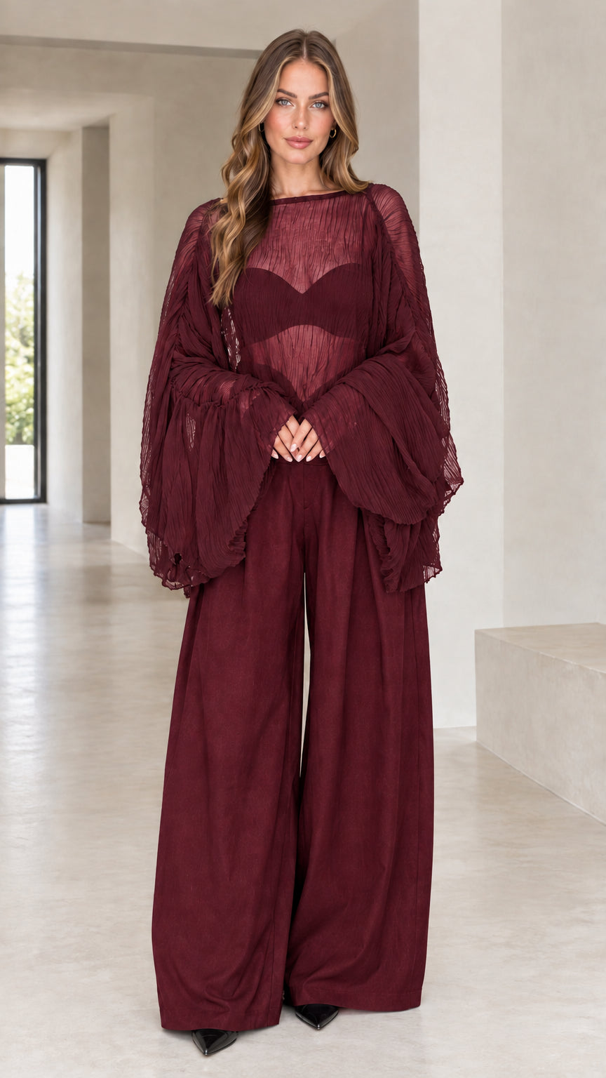 Front view of woman wearing burgundy sheer pleated bell sleeve top and wide-leg pants set