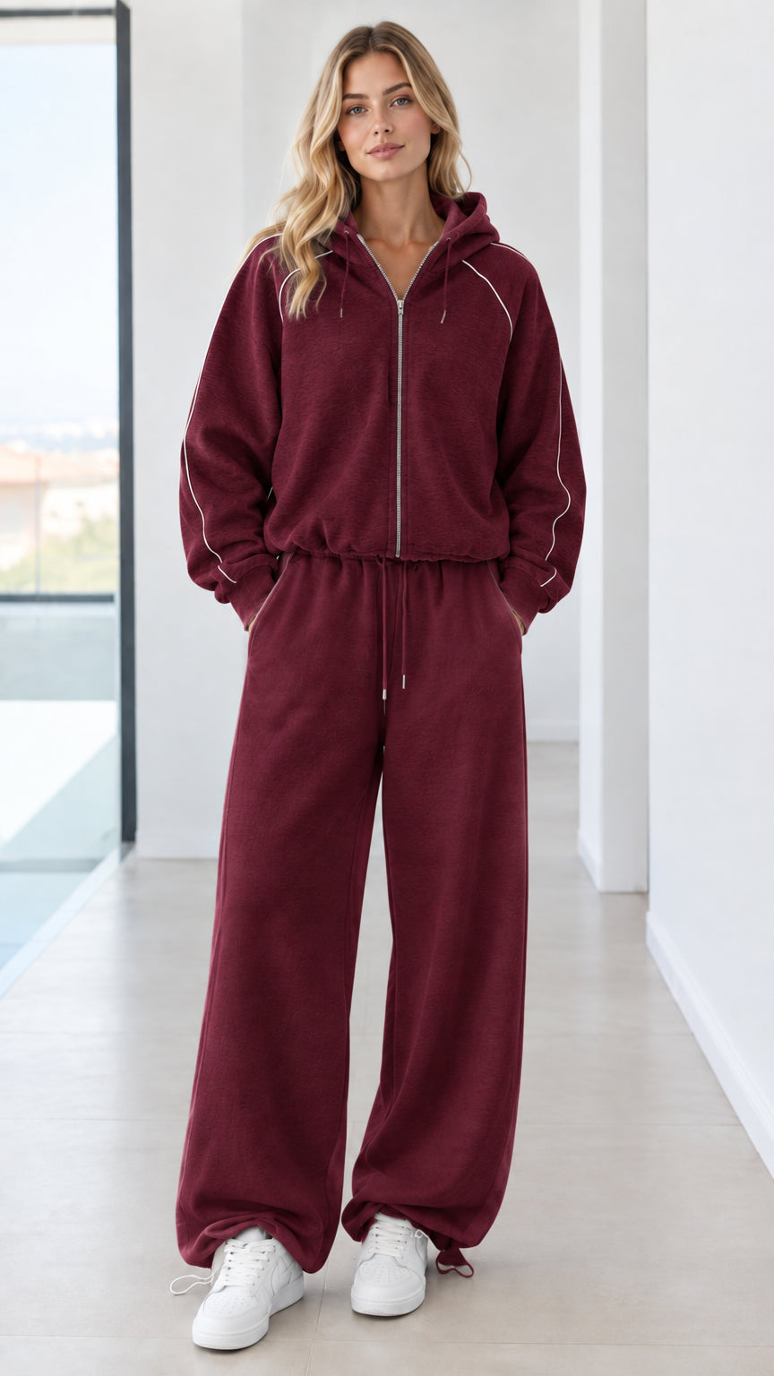 Full body studio shot of model wearing burgundy wine zip-up hoodie and wide-leg sweatpants set
