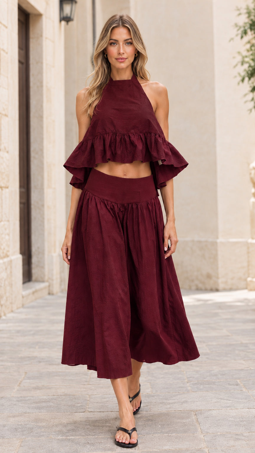Front full-length view of model wearing burgundy red halter crop top and midi skirt set