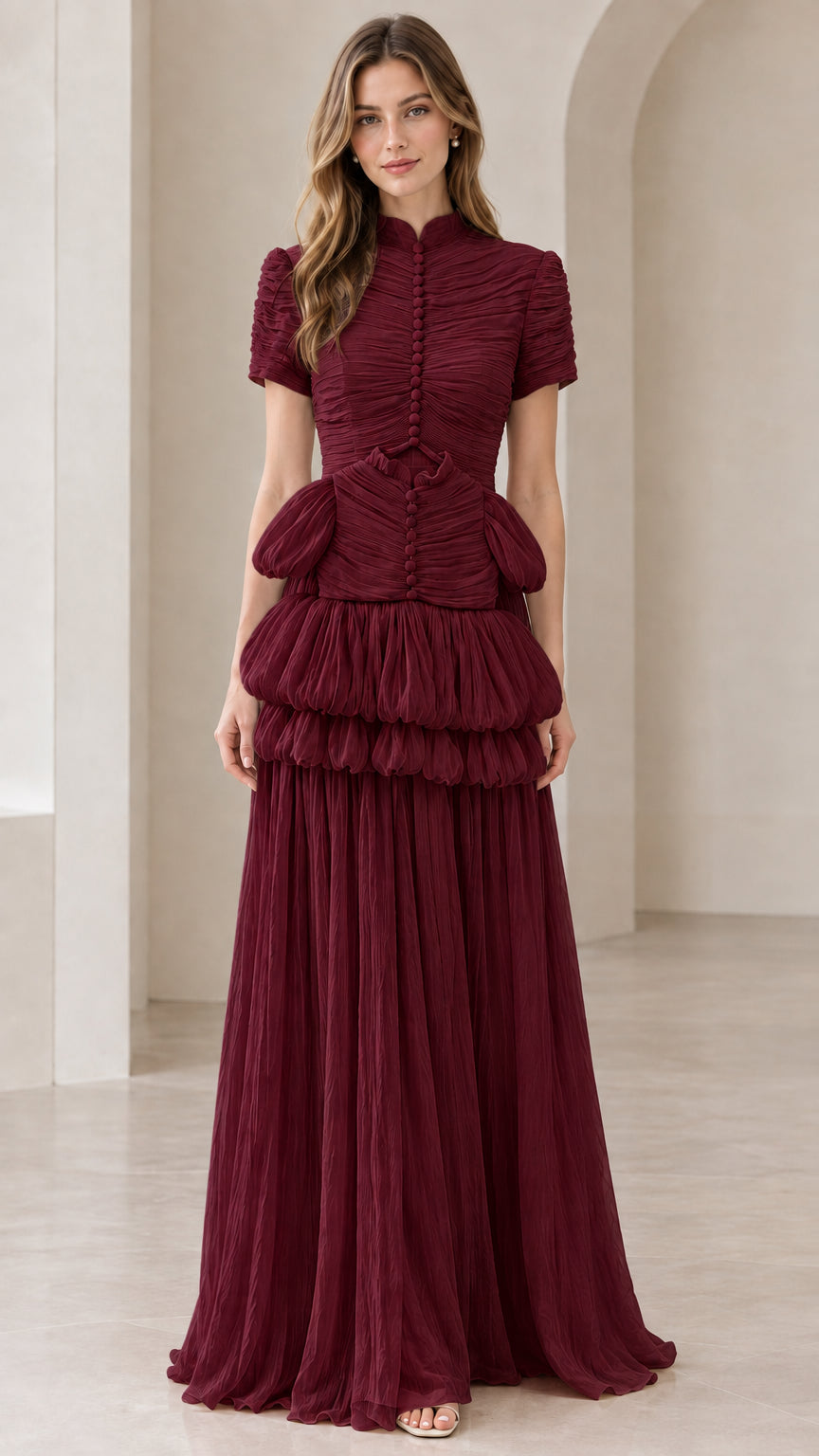 Front view of model wearing burgundy wine red mock neck tiered pleated gown