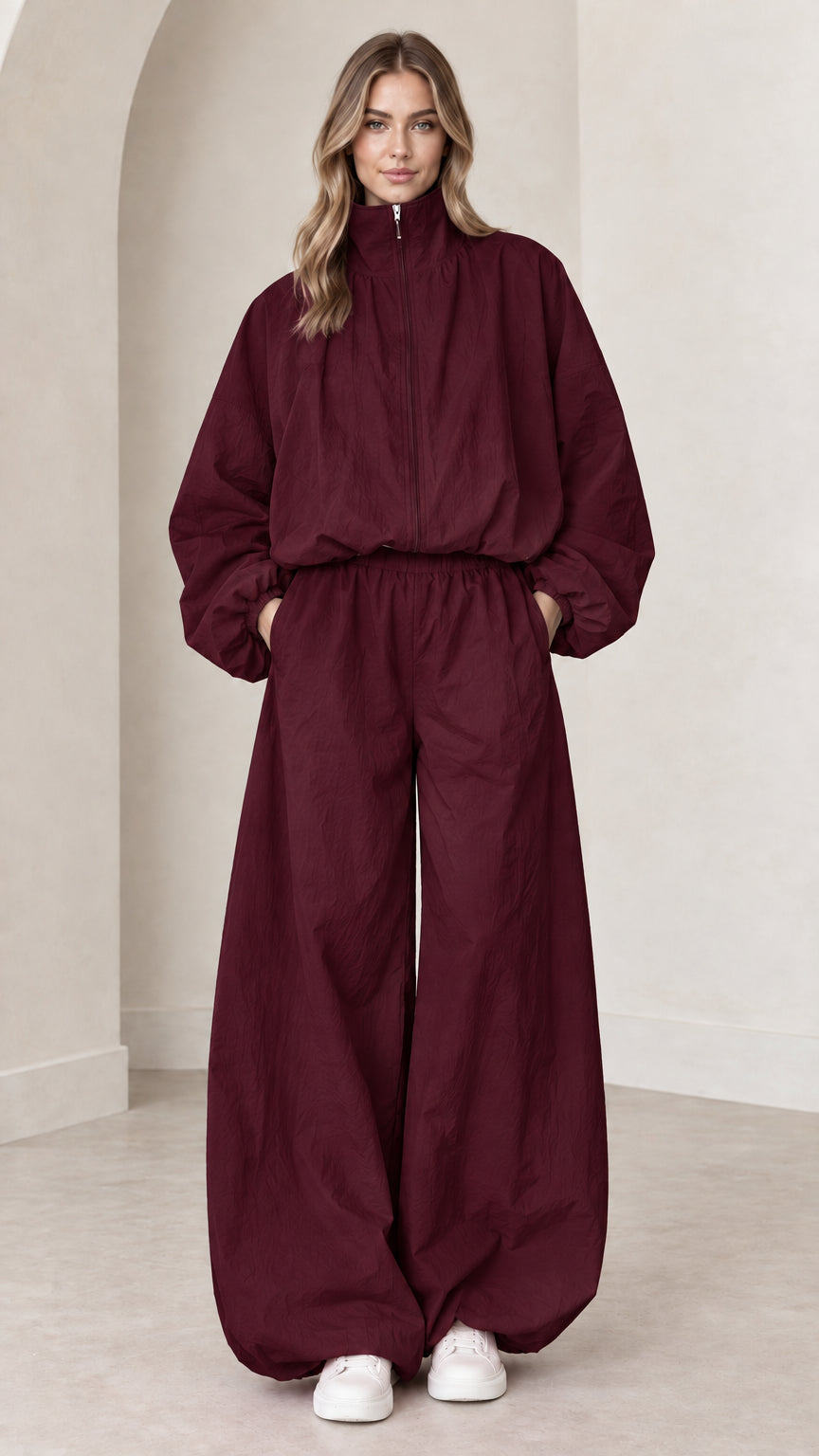 Model wearing deep burgundy wide-leg parachute jumpsuit with front zip
