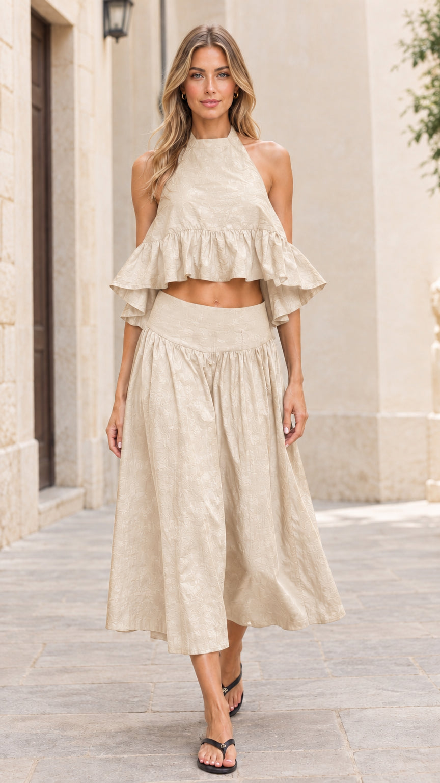 Front full-length view of model wearing beige oatmeal halter crop top and midi skirt set
