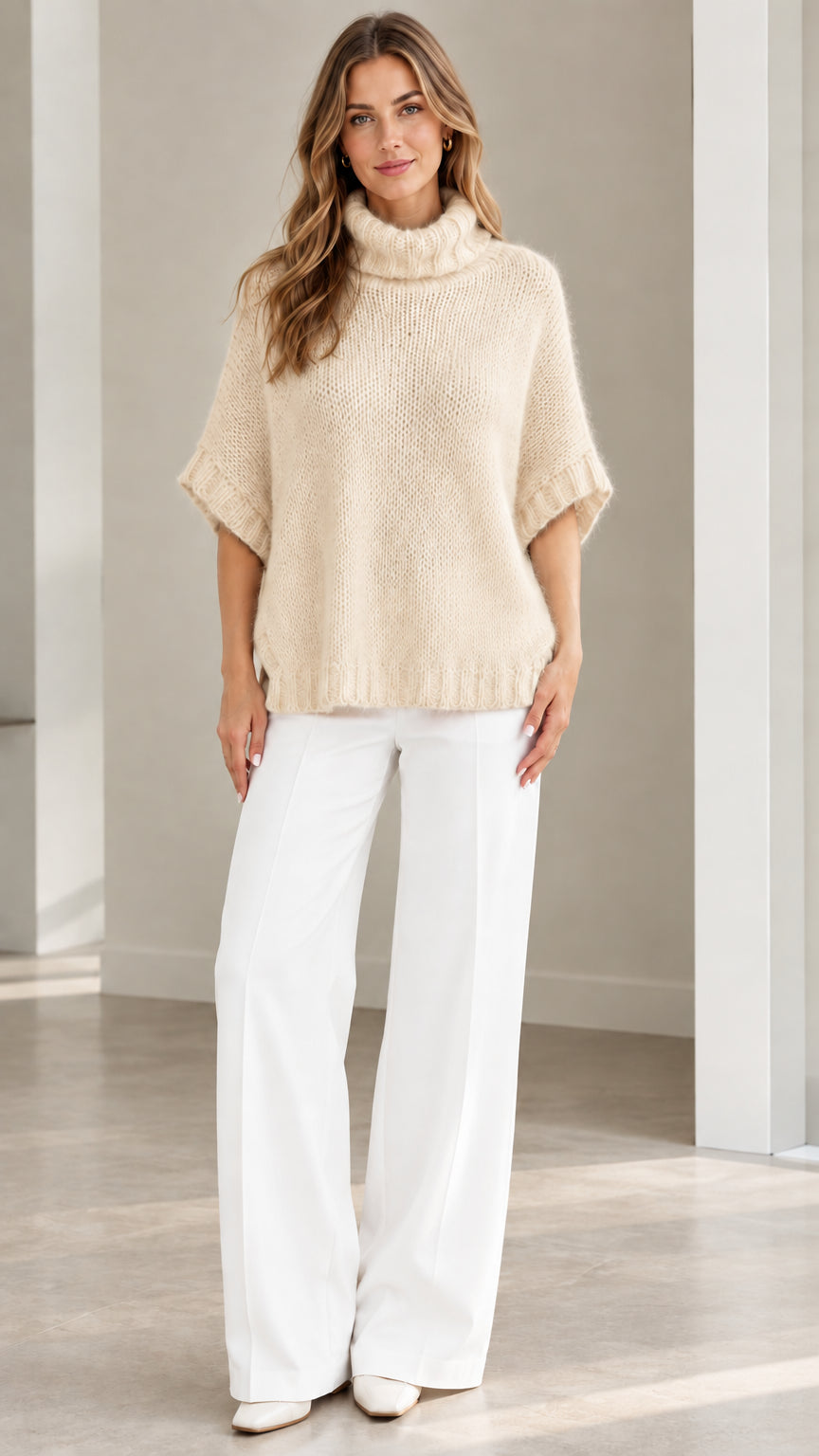 Model wearing Cream beige fuzzy knit turtleneck poncho sweater