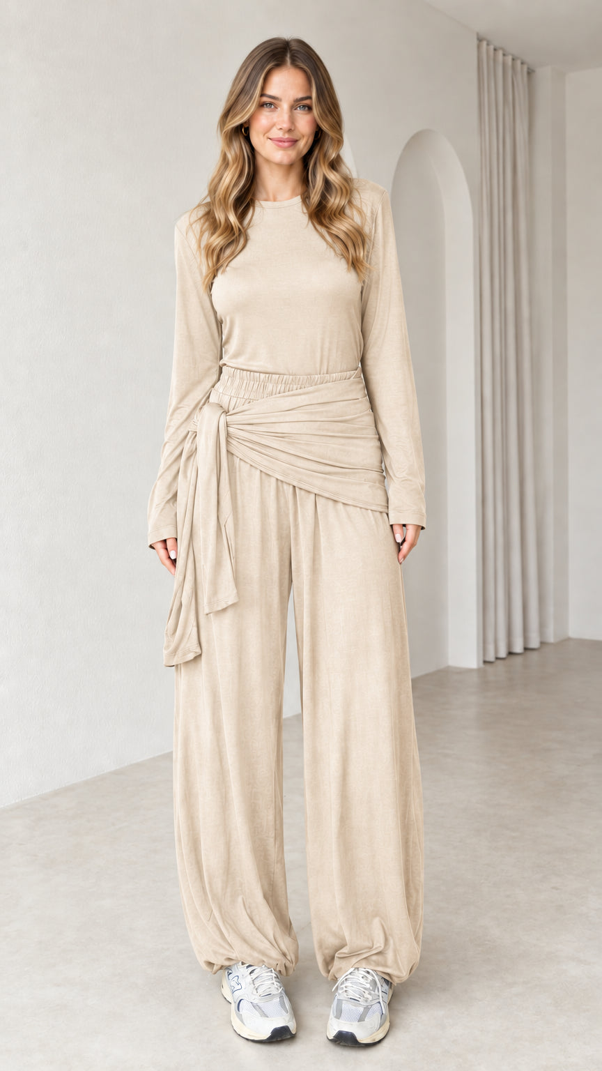 Front view of woman wearing beige 2-piece long sleeve draped tie lounge set