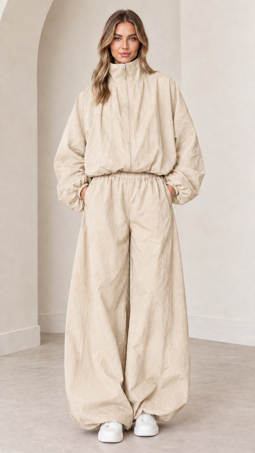 Model wearing beige cream long-sleeve parachute jumpsuit with relaxed silhouette