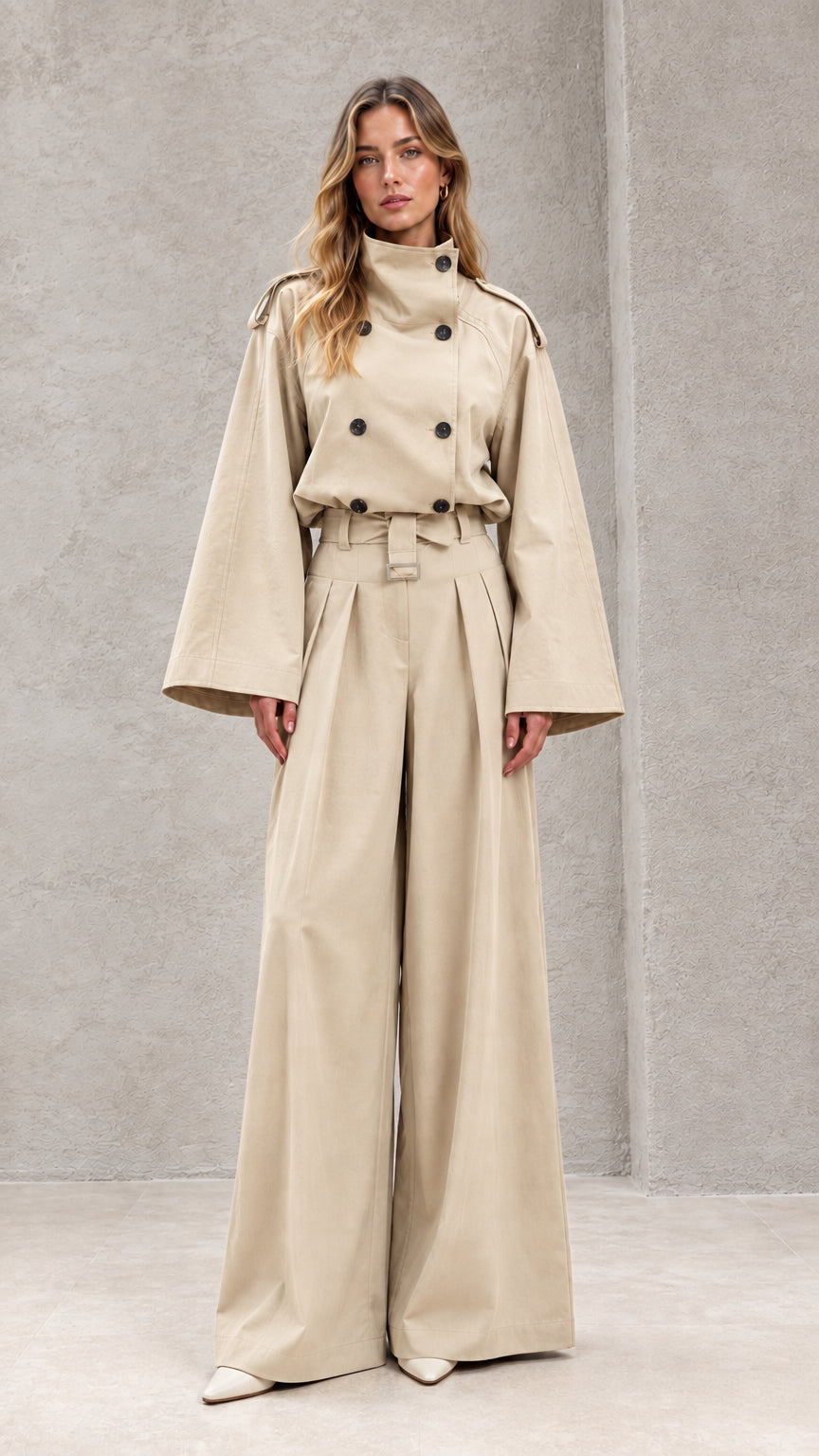 Front full-length view of model in sand beige double-breasted wide-leg trench jumpsuit